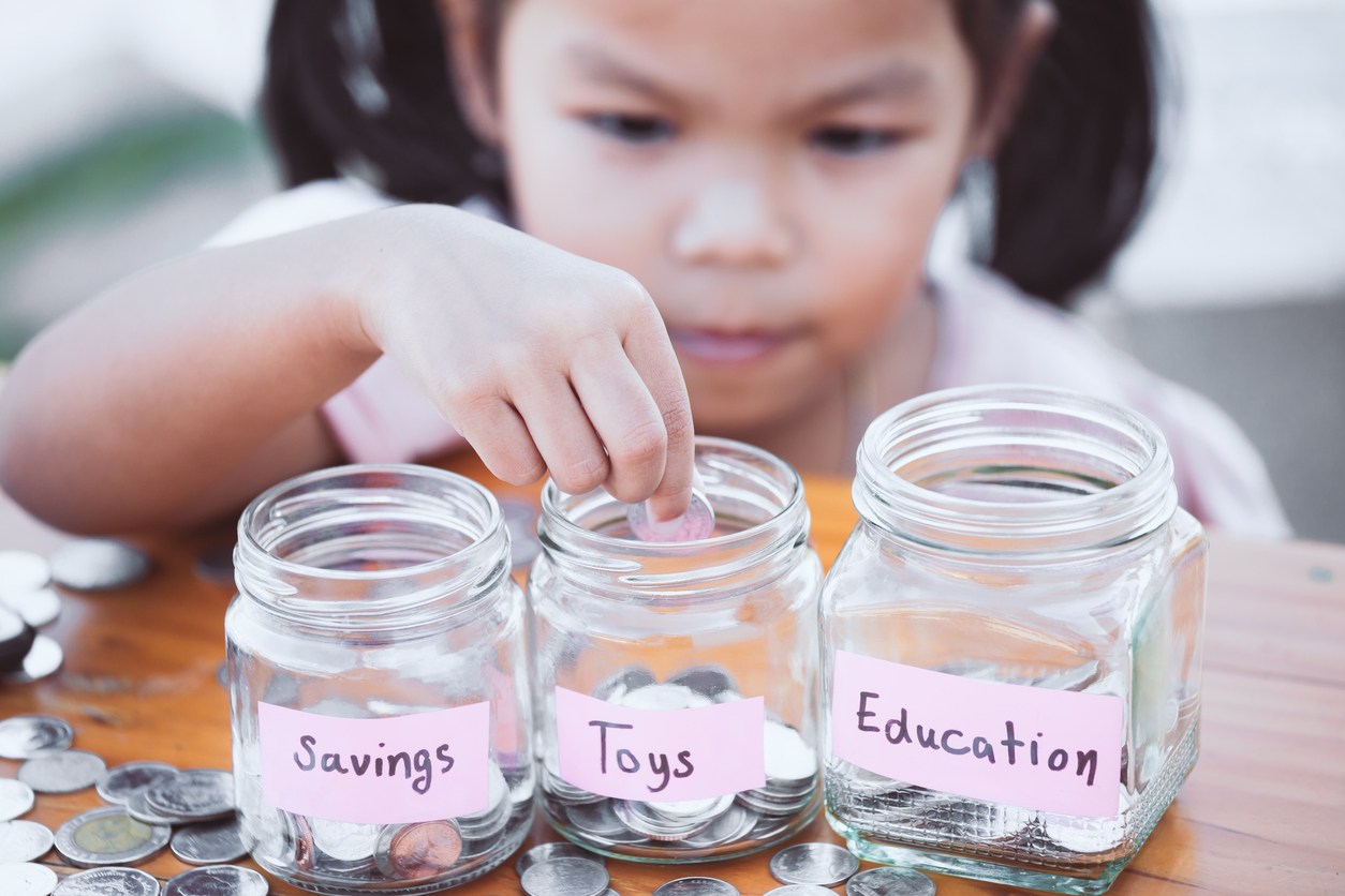 A little girl putting money in jars