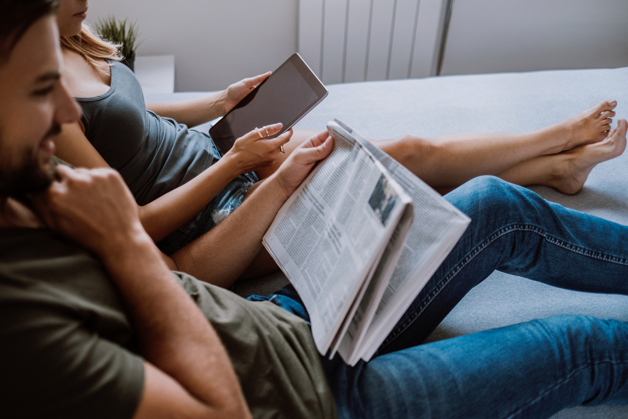 Couple sitting together reading the news