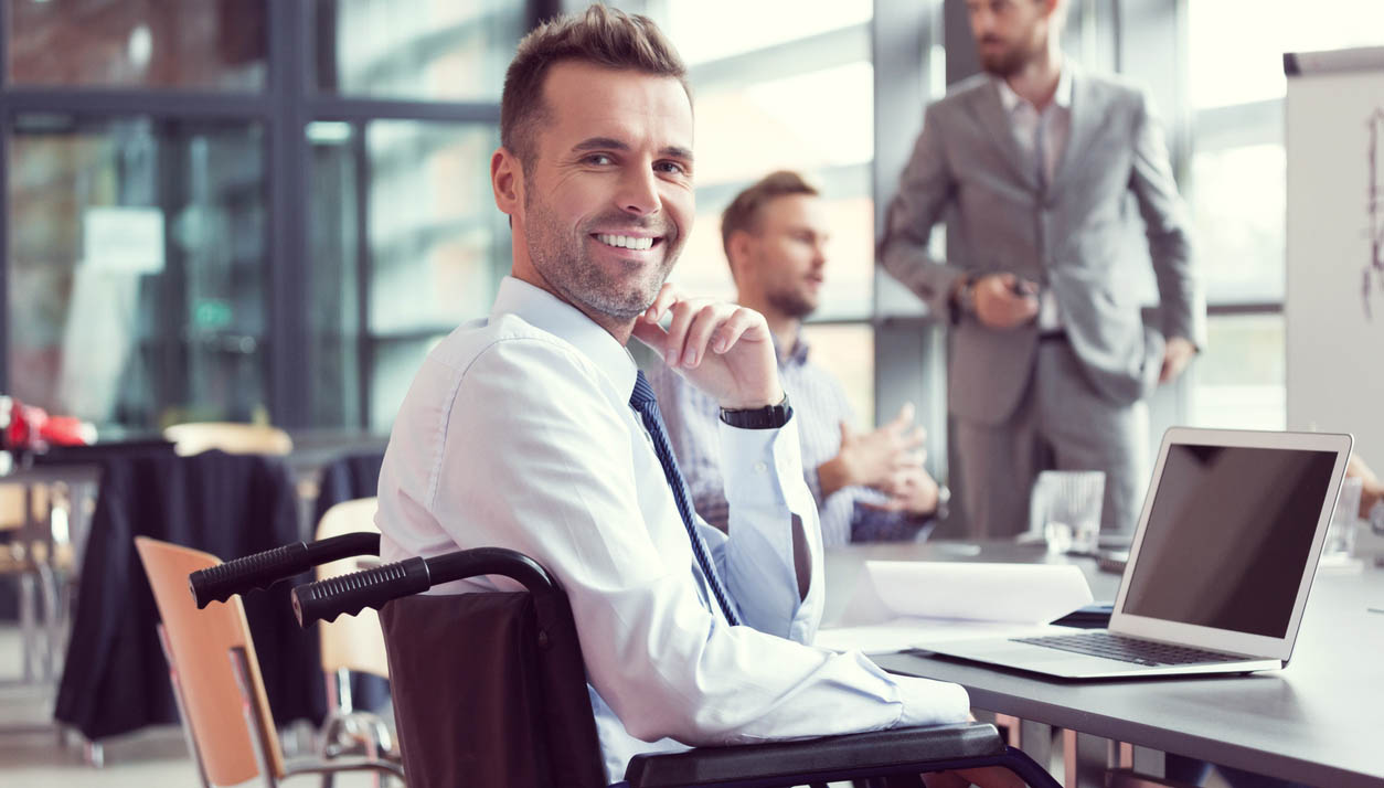 Man in wheelchair smiling at desk